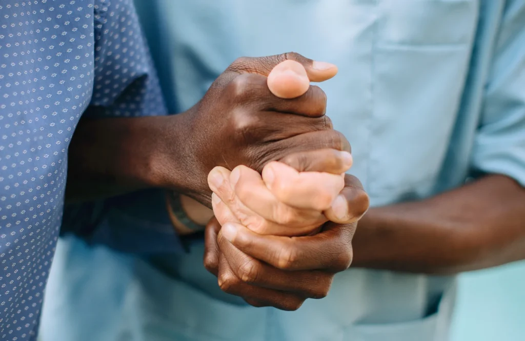 Close up of caregiver holding a senior man's hand.