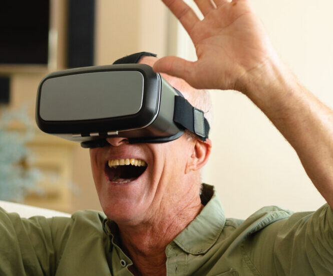 Excited grandfather playing with a virtual-reality video game headset.