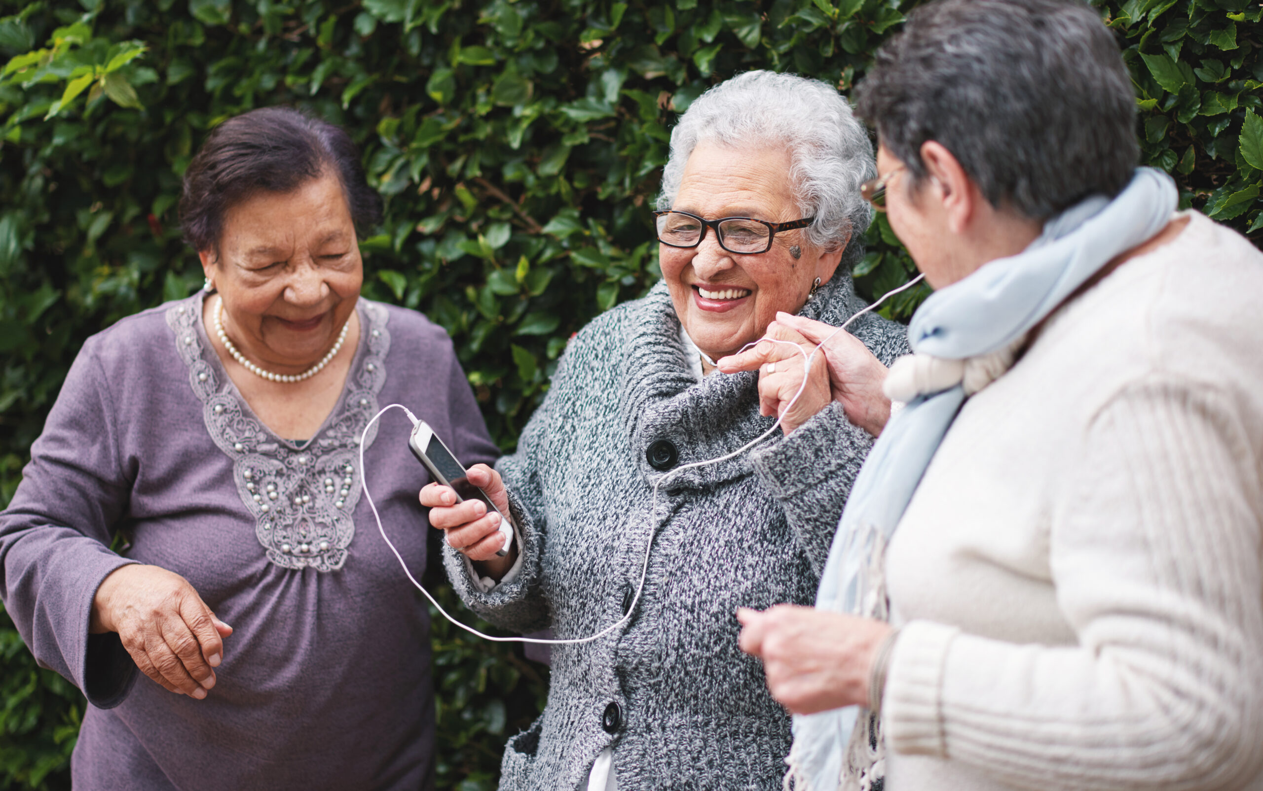 Happy old women listening to music on smartphone wearing earphones smiling enjoying fun celebrating.