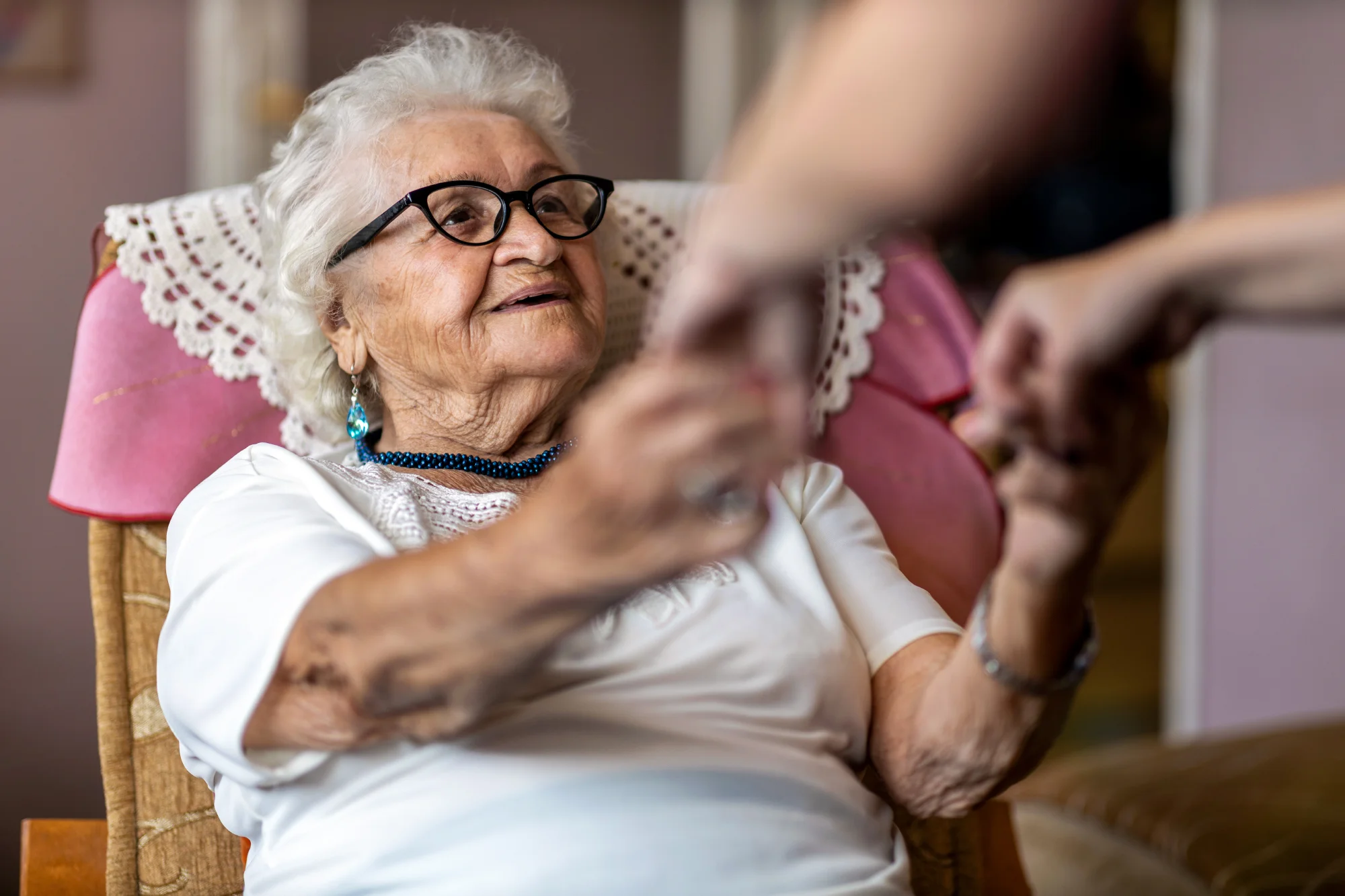 Caregiver helping senior lady out of chair.